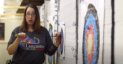 Coach Laura Reed pulling an arrow out of a target using both hands.