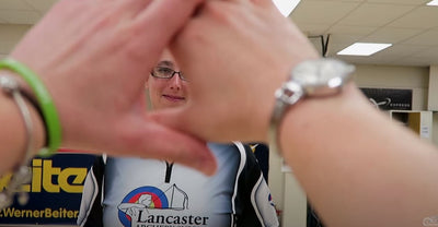 Coach Heather Pfeil stretches her hands out creating a triangular hole with her index fingers and thumbs to see Coach Laura Reed.