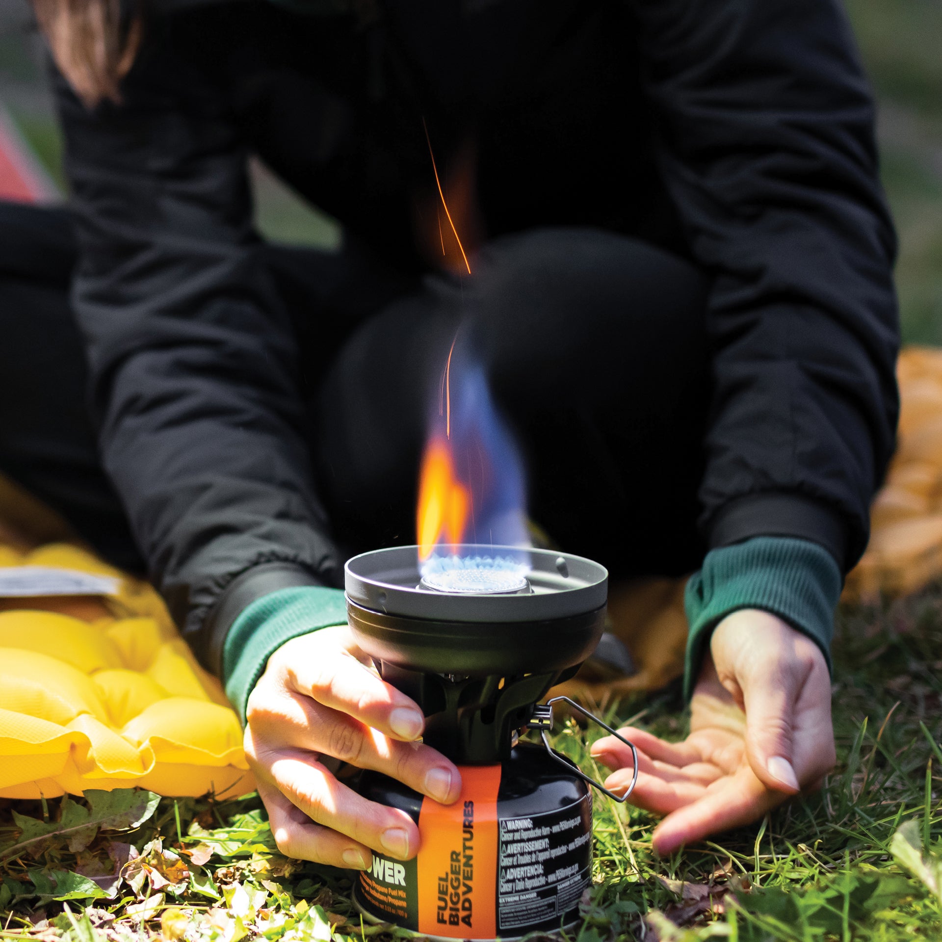 women lighting up a jetboil stove sitting on a inflated pad.
