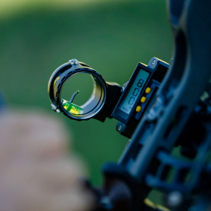 Close-up of a bowsight with a digital reticle on a blurred green background