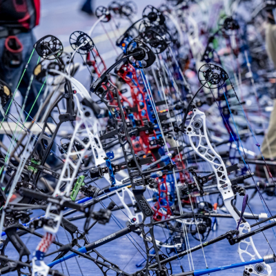 several indoor target compound bows on stands lined up at a competition