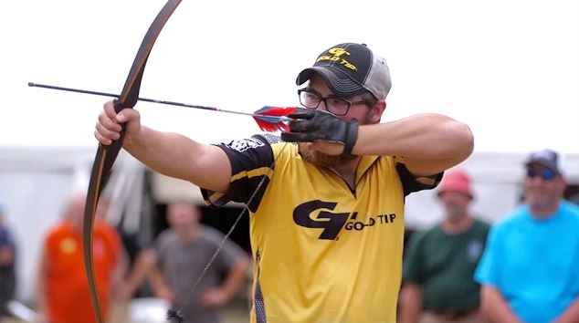 Chris Hurt wearing a Gold Tip jersey draws his longbow.