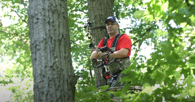 P.J. Reilly stands in a tree stand preparing to draw back his hunting bow.