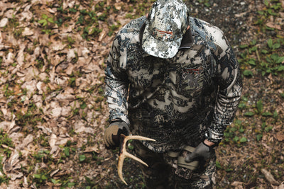 A hunter wearing SITKA Gear Elevation II camo, picked up a deer shed.