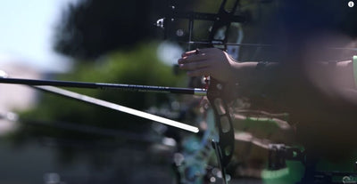 Youth archer aims their Olympic recurve bow at an outdoor target.