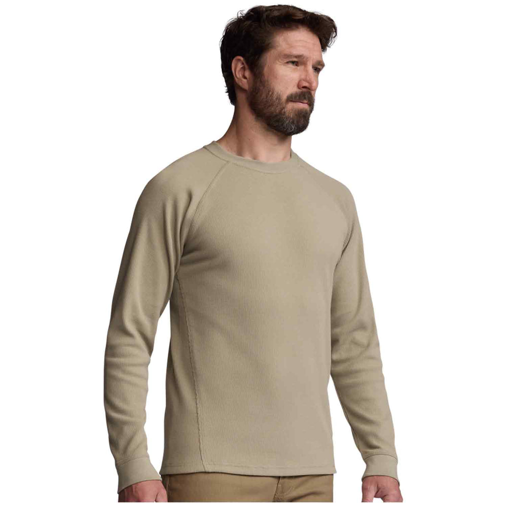A man wearing a light beige long-sleeve crewneck shirt, shown from the waist up against a plain white background.