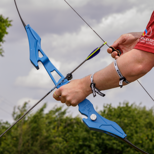 Person holding a blue archery bow with a blurred background