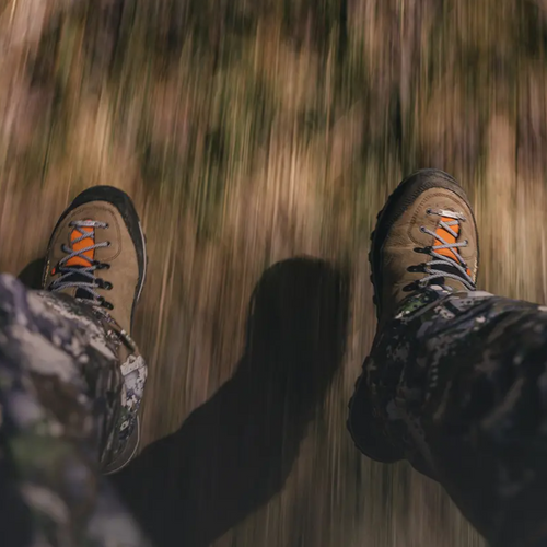 Close-up of hiking boots stepping onto a grassy path