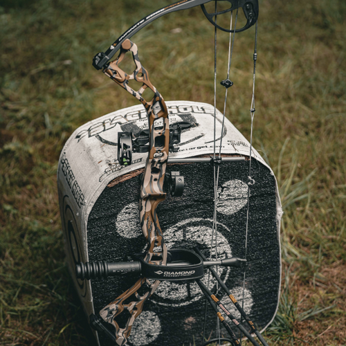 Close-up of a compound bow with a camo pattern on a grassy background