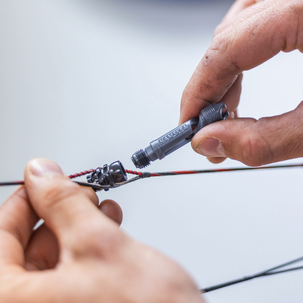 Close-up of hands working with a compound bow string on a light background