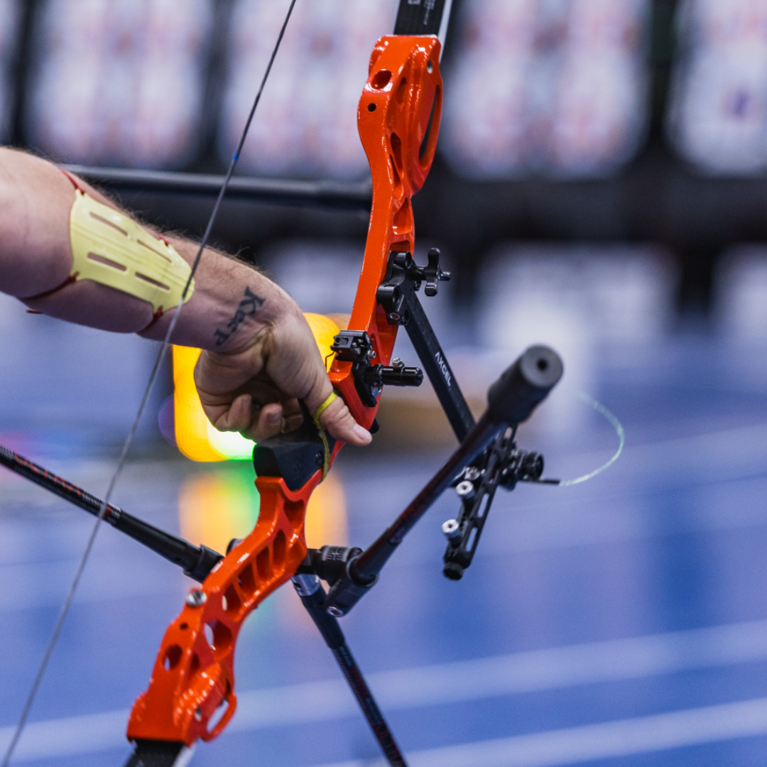 Person holding a red compound bow with a blurred background